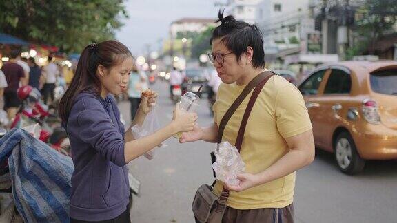 亚洲男人和女人在路边分享街边小吃