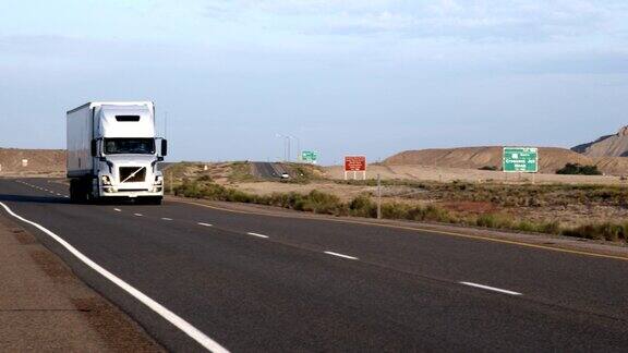 一辆长途半卡车和拖车在沙漠的四车道公路上行驶在黎明或黄昏