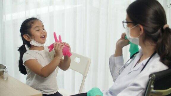 医生给小女孩打疫苗前和小女孩玩耍注射冠状病毒疫苗