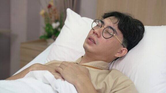 亚洲男性病人在医院休息时在床上感到不适