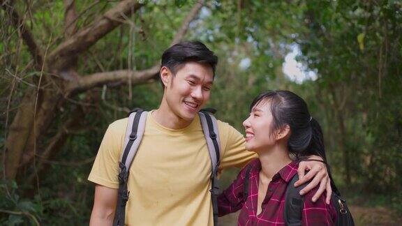 年轻的亚洲男人和女人的朋友一起在森林里旅行的肖像情侣们在大自然中感到清新和放松站在一起拥抱然后微笑着看着镜头