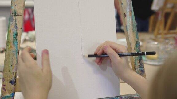 一个小女孩在艺术工作室用铅笔在画布上画素描
