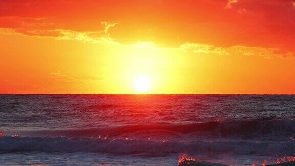 海洋海滩日出与橙色的天空云燃烧的太阳光线在海浪和飞翔的鸟