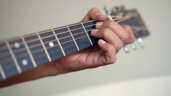 高级男子手指在原声吉他指板上做和弦