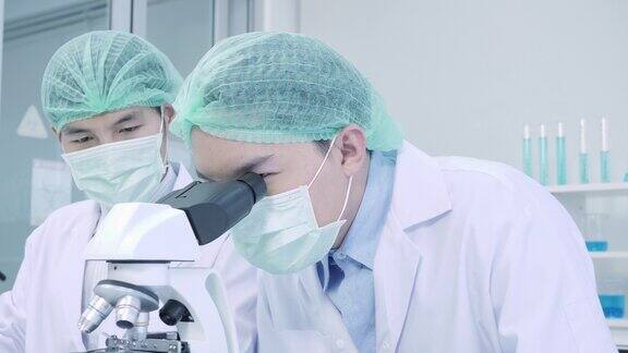 科学家在实验室用显微镜观察血样做冠状病毒疫苗实验