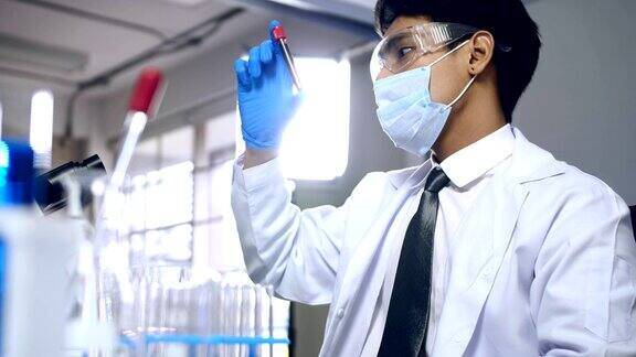 亚洲科学家正在做一些研究在实验室的试管中检查液体