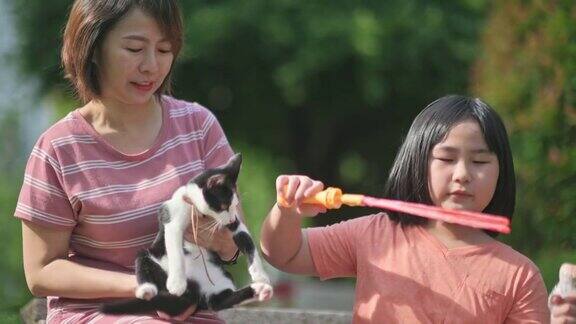 周日早上亚洲华人妈妈和女儿在后院和猫玩泡泡在闲暇时间聚在一起