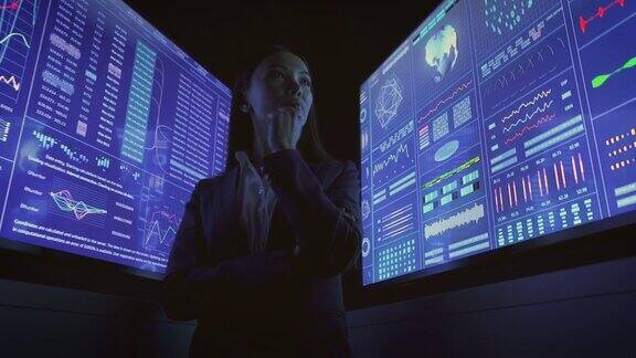 在黑暗的实验室里站在蓝屏幕旁边的女商人