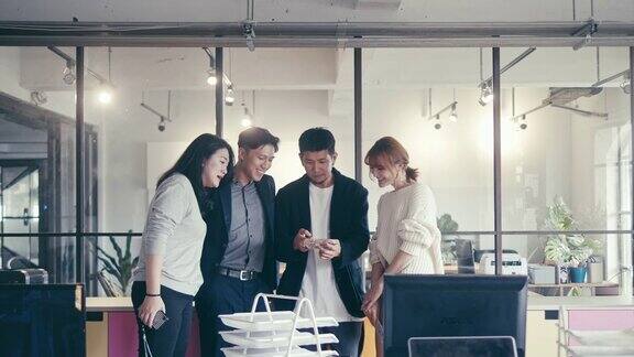 一群亚洲千禧一代在金融科技公司办公室用智能手机看视频(慢镜头)