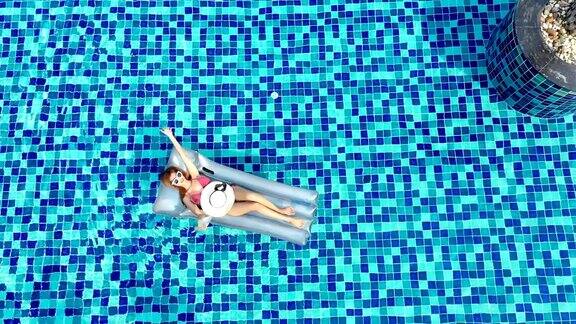 无人机鸟瞰图上的妇女漂浮在蓝色游泳池享受度假热带目的地假期