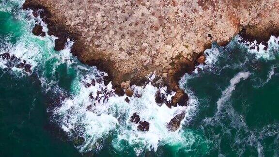 鸟瞰图的岩石海岸线和撞击悬崖的海浪