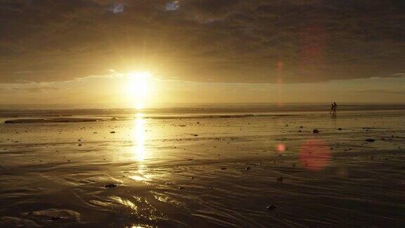 慢镜头:日落时退潮时人们在沙滩上行走的剪影漂亮的耀斑和空间用于复制或文本布鲁姆澳大利亚西部