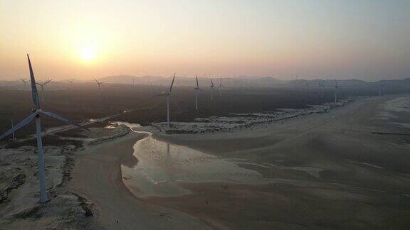日落时分海滩上的风力发电厂