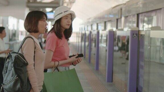 两名女游客在火车站站台等车时聊天RAWVDO拍摄的4k慢镜头