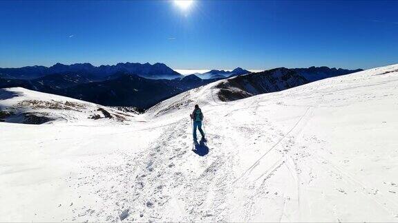 在奥地利卡林西亚的卡拉万克斯雪峰上背着背包的活跃女子在霍乔比尔的山峰上欣赏风景滑雪之旅朱利安阿尔卑斯山阳光灿烂的冬日自由