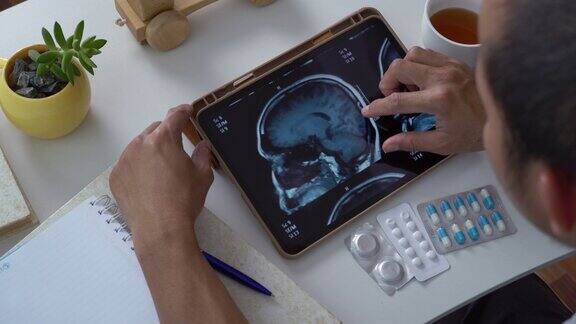 亚洲男性通过电子平板电脑进行脑部核磁共振扫描以了解自己脑瘤的阶段