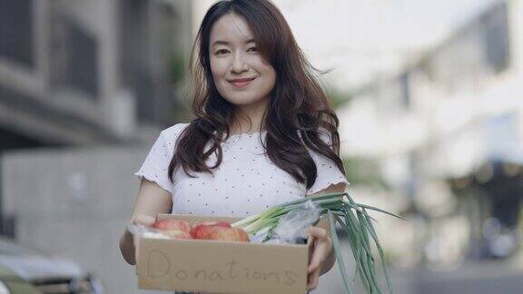 亚洲女性志愿者将食物放入捐赠箱