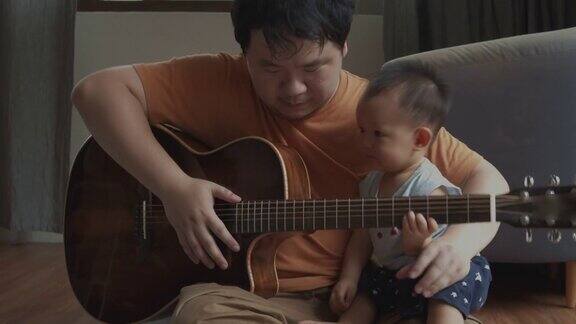 父亲和他蹒跚学步的儿子在家里的客厅里弹吉他