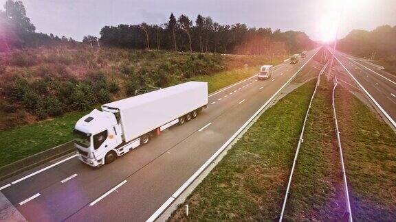 带有货运拖车的商业卡车在空旷的公路上行驶阳光在背景中闪耀
