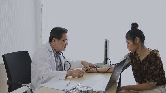 医生在医院的办公室里用血压计给女病人检查