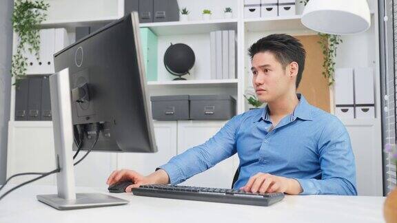 亚洲英俊的商人使用笔记本电脑在办公室工作有魅力的专业男性员工坐在桌子上感到快乐享受在公司工作场所的休闲时间