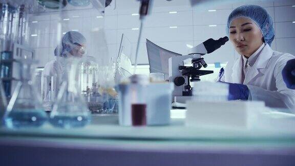 研究有害生物样本的女性小组亚洲女医生使用显微镜