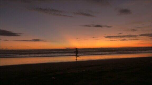 一个跑步者在日落或日出时沿着海滩跑步的单一剪影