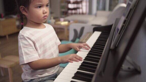 亚洲小女孩在家练习弹钢琴在平板电脑上观看教程在线学习乐器