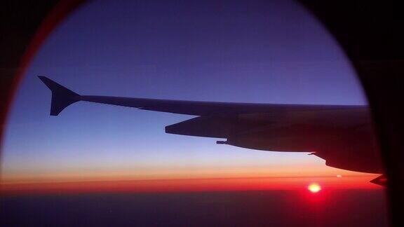 日落日出飞行飞机窗口视图与机翼