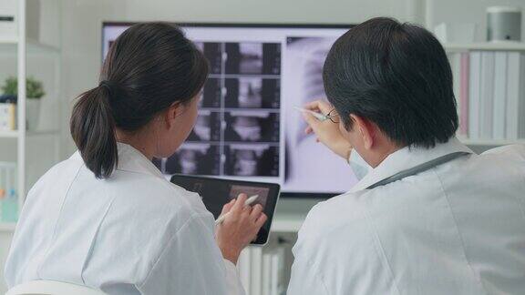 医疗队亚洲男、女医生在医院电脑上检查病人的x线图像讨论结果医疗保健