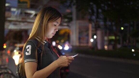 女性在晚上用智能手机请求和等待优步