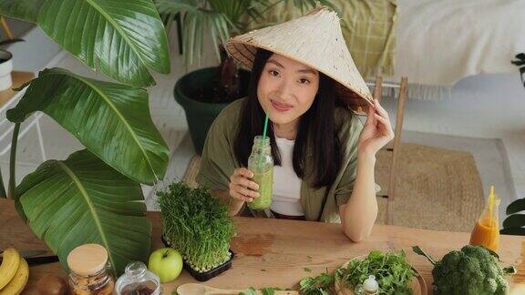 年轻和快乐的亚洲女性在传统的锥形帽子喝健康的滋补冰沙