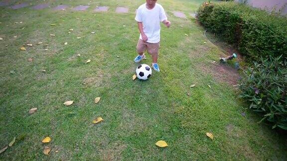 亚洲小孩在公园里踢足球在房子的后院假期和健康