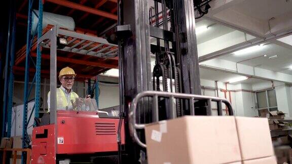 亚洲华人高级工人使用叉车在工业工厂搬运货物