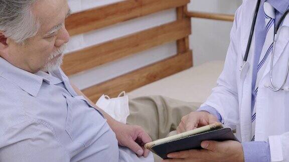 健康医生访老夫妇家访期间医生检查检查一位祖父在平板上描述病情
