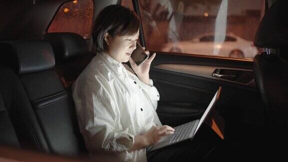 一位女士在汽车后座上使用笔记本电脑和智能手机