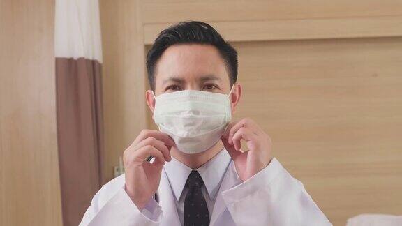 亚洲男医生戴上外科防护口罩预防冠状病毒大流行医护人员在医院穿医生袍戴口罩的肖像健康职业新常态生活方式