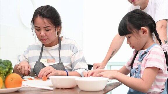 快乐的亚洲母亲和女儿坐在餐桌前一起准备饭菜的肖像