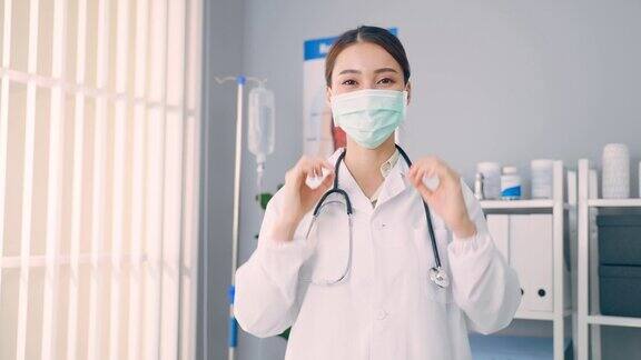 亚洲女医生摘掉外科防护口罩的肖像漂亮的护理医师身着长袍自信地站在恢复室检查工作圆满成功后