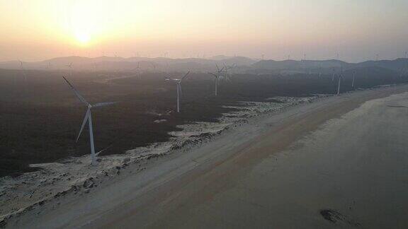航拍雄伟的风力发电厂和海滩防护林日落景色