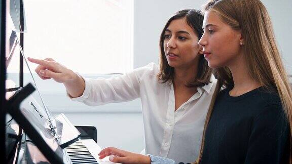 在音乐课上女学生与老师一起弹钢琴