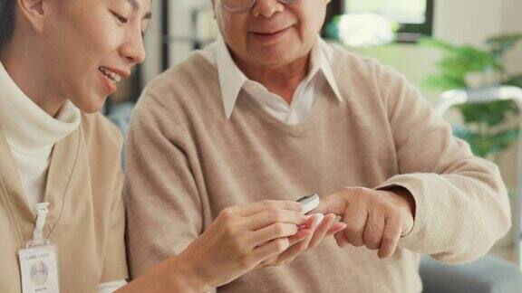 特写年轻的亚洲女性个人护理人员照顾老男人使用指尖脉搏血氧仪检查血液氧压在家里