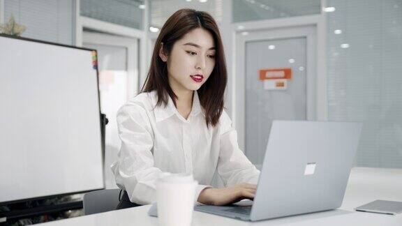 亚裔中国美女经理在办公室用笔记本电脑打字工作