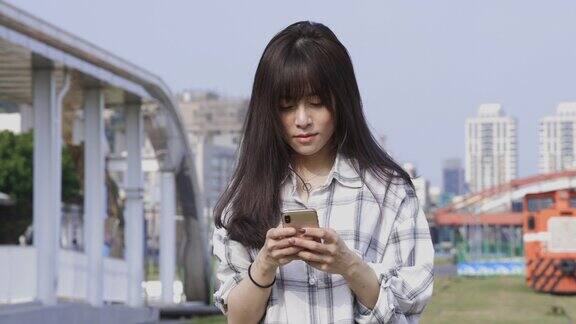 一名亚洲女性在城市街道上使用智能手机