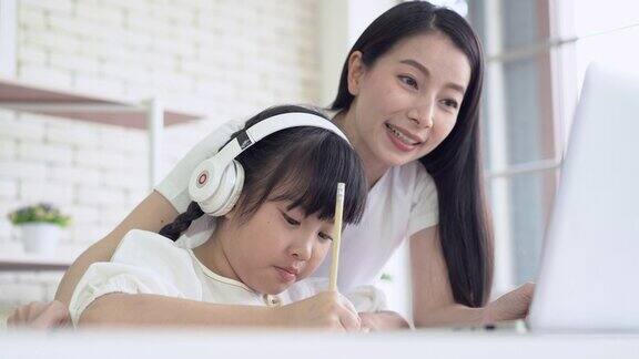 肖像亚洲小女孩开始参加e-learning在线教育班级小组活动从学校老师在家里年轻的母亲在在线课程开始前准备好了耳机