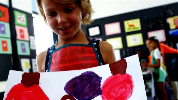 快乐的女孩在绘画课上展示她的绘画