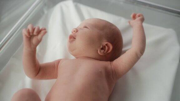 可爱的小白种人新生儿躺在医院的病床上在托儿所诊所活泼健康的小宝贝《医疗保健、产妇和父母概念》高角度特写肖像