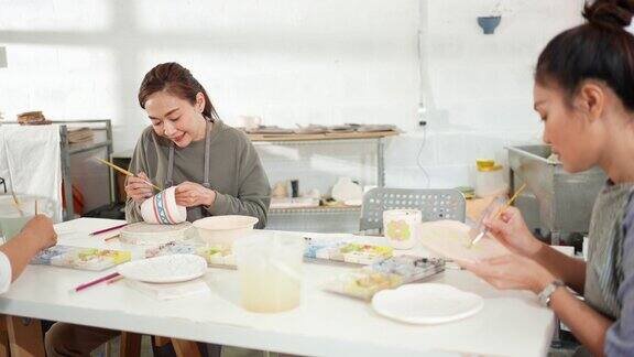 4K亚洲妇女画自制陶瓷马克杯与朋友在陶瓷工作室