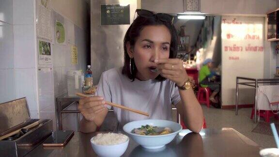 年轻的亚洲女人吃泰国面条泰国街头小吃