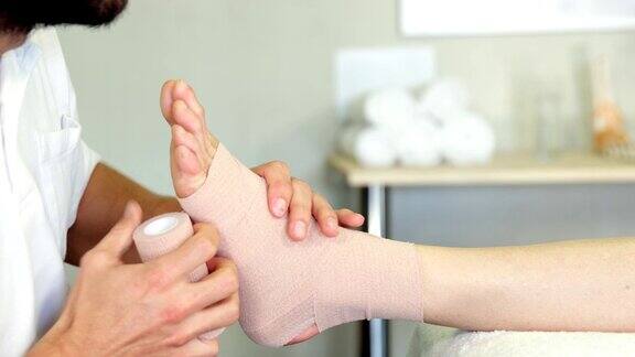 理疗师给病人受伤的脚包扎